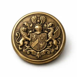 A zinc alloy 3D raised crest button with an antique brass finish, featuring a soft rounded edge and crisp raised detailing. Single button on a plain white background, perfect for e-commerce display.