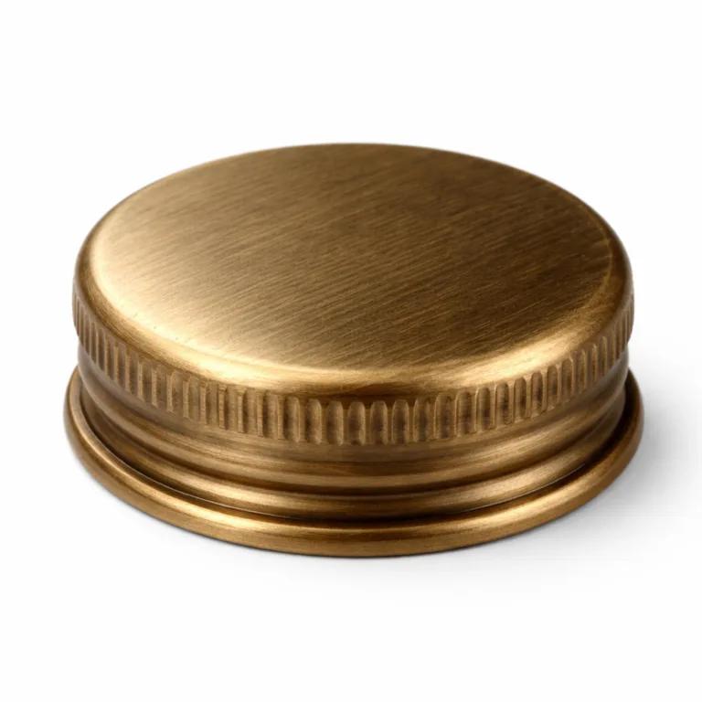 A single antique brass bottle cap with a brushed finish and subtly rounded edge, photographed in a high realism, studio-lit setting with sharp details. Suitable as a functional and stylish accessory for bottles.