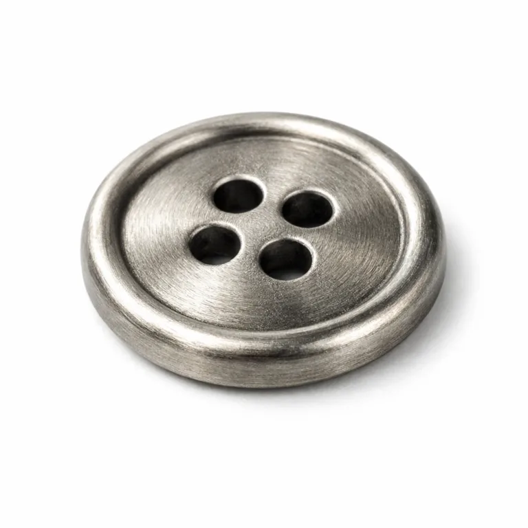 A highly realistic product shot of a brushed nickel shirt button in antique silver finish with a softly rounded edge. The vintage texture adds style to both classic and modern garments.