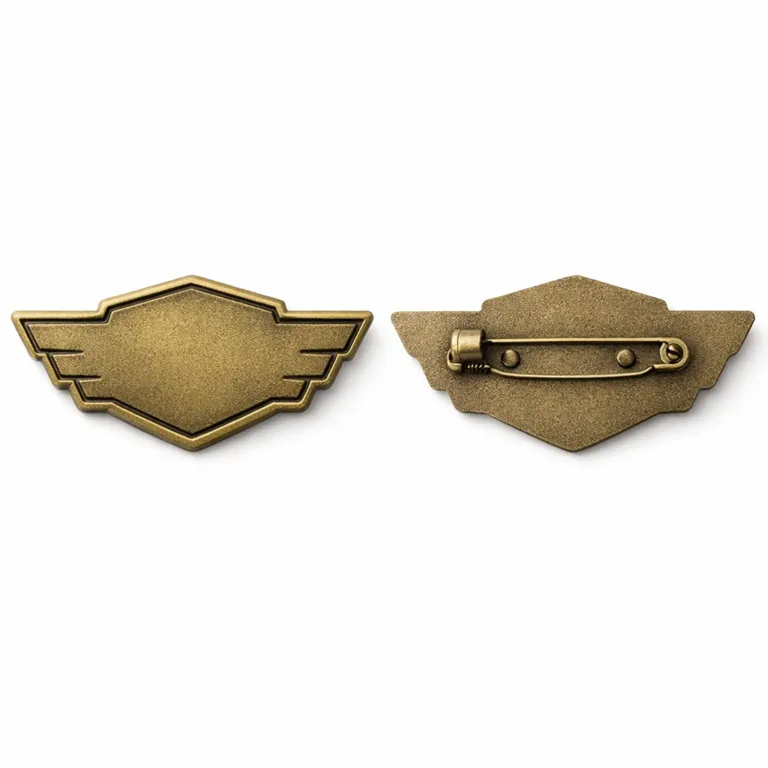A die-cast badge made from brass, finished in antique brass plating, featuring a flat 2D emblem with sandblasted matte surface. Shows a safety pin back attachment, highlighting realistic manufacturing details.
