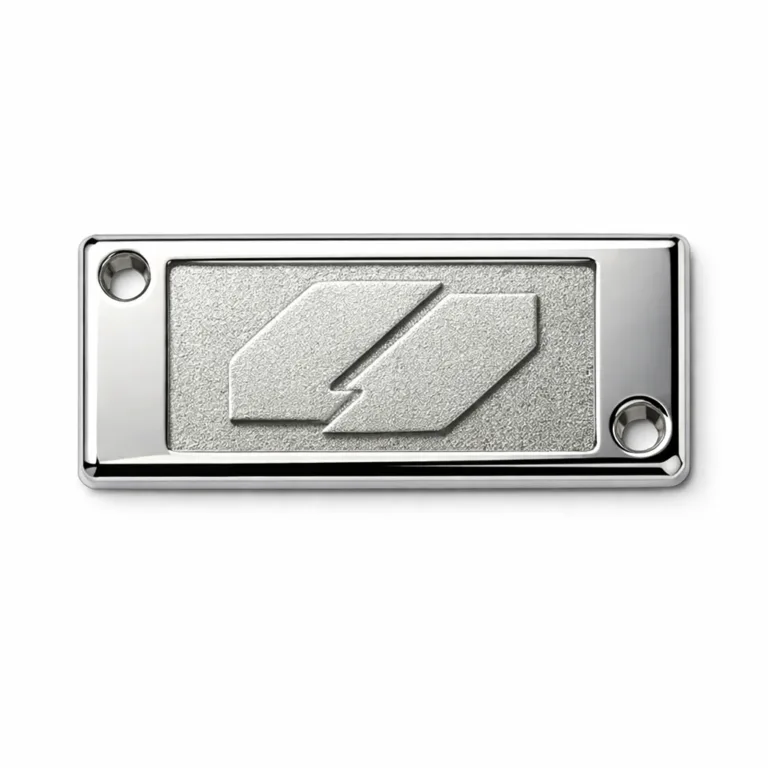 A rectangular die-cast metal logo tag with shiny nickel plating and a sandblasted matte emblem area. The tag includes small screw holes for mounting.