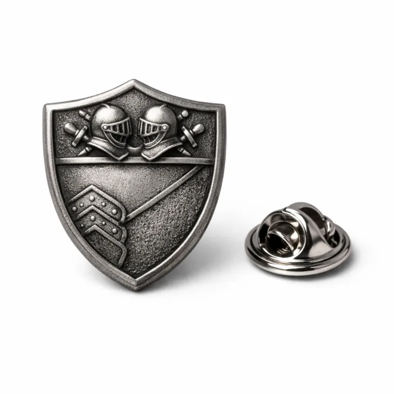 Lapel pin badge in a classic shield silhouette, featuring an antique silver finish with a sandblasted matte surface, 3D relief central design, and butterfly clutch backing. The textured finish highlights the intricate metalwork.