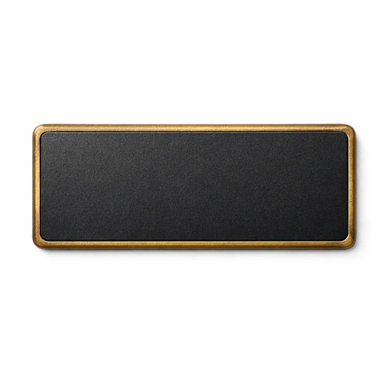 A detailed e-commerce product photo of a matte black nameplate with an antique brass-finished frame, sandblasted surface, crisp white engraving, and softened rounded corners.