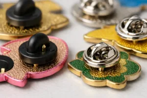 A detailed studio image showing both rubber and butterfly clutch pin backings attached to enamel pins, illustrating their hardware and build quality.
