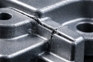 Close-up view of a zinc alloy part highlighting the sharp edges and visible burrs that quality control must address during inspection.