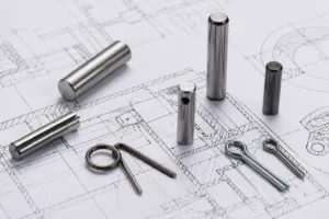 A variety of metal pins are displayed on an engineering drawing, illustrating the importance of precise pin selection in avoiding mistakes during the pin ordering process.