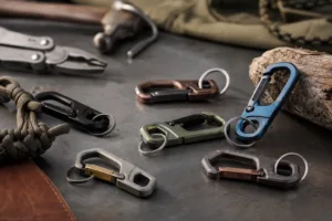 A realistic product image showing multiple carabiner keychain styles with outdoor-oriented finishes and branding details.