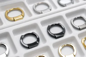 A realistic close-up showing multiple custom metal phone ring samples in zinc alloy, stainless steel, and plated finishes for material comparison.