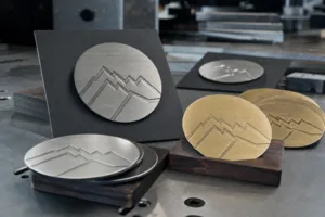 A realistic manufacturing-oriented image showing etched metal coaster samples in multiple finishes for material and appearance evaluation.